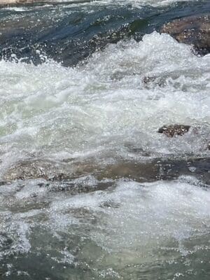 Close-up view of rushing water over rocks, illustrating the revitalized flow of the Klamath River following the dam removal, symbolizing the restoration of natural habitats and river ecosystems.