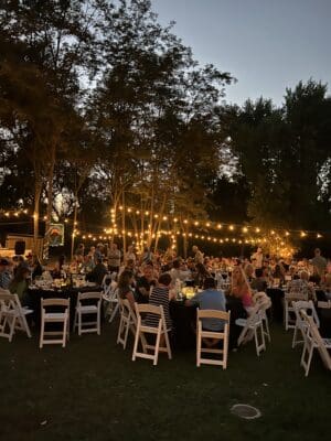 Outdoor celebration event at Camp Lotus with attendees gathered around tables under string lights, supporting Friends of the River and their mission to protect California's rivers.